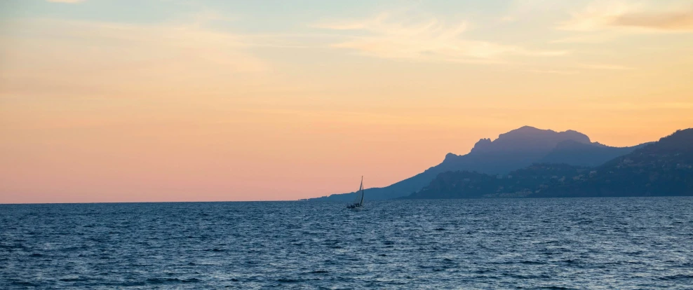 a sailboat in the water with a mountain in the background