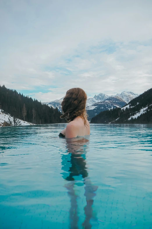 a woman sitting in a pool in the mountains