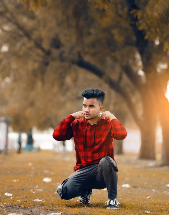 a young man is posing for a picture in the park