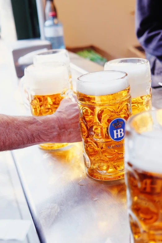 beer in glasses are being served to someone at a bar