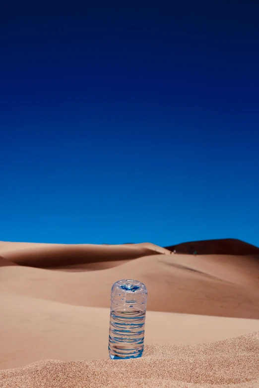 a bottle in the desert with a blue sky in background