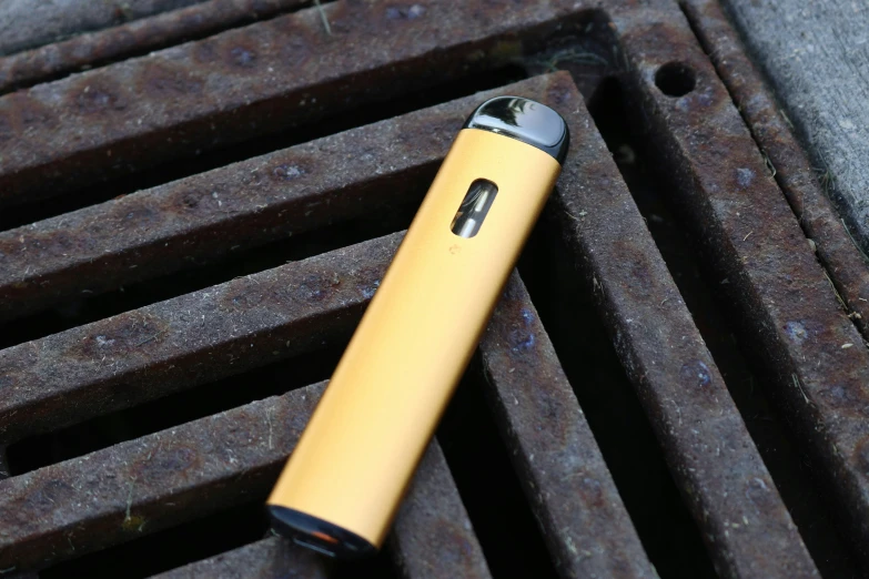 a yellow lighter laying on a grey metal grill grate