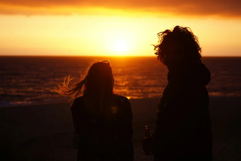 two people are standing outside at sunset