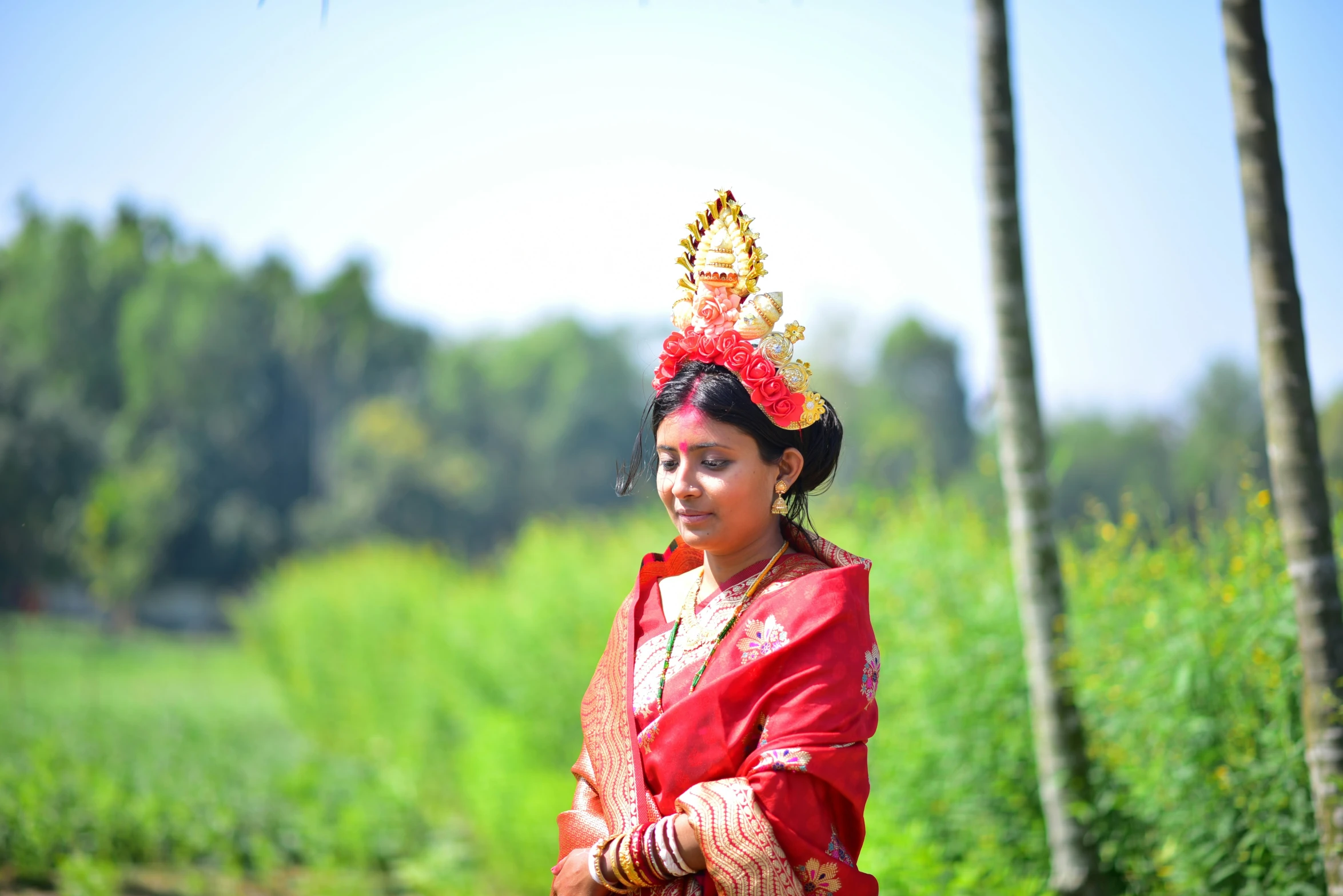 an asian woman in red and yellow dress poses in front of her house