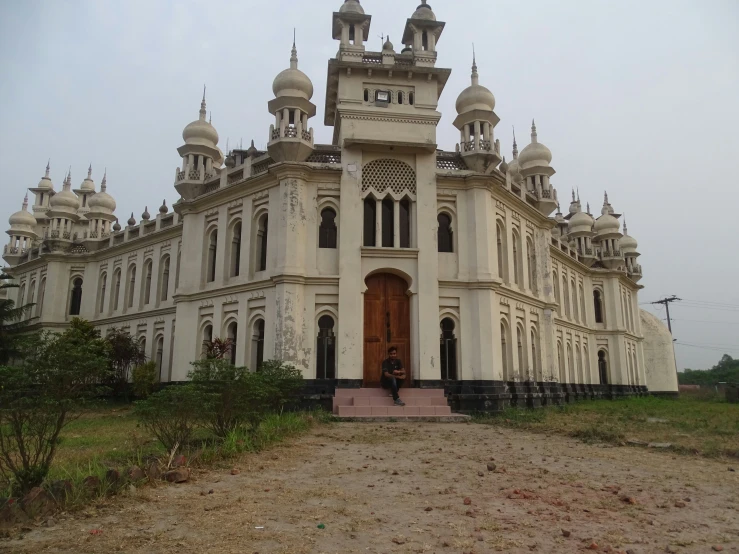 a large building with four towers on a dirt field