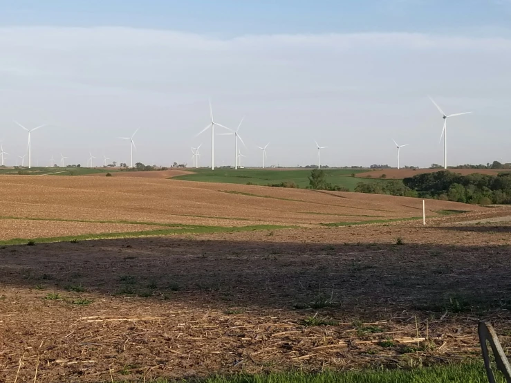 wind turbines are seen on a field near a fence