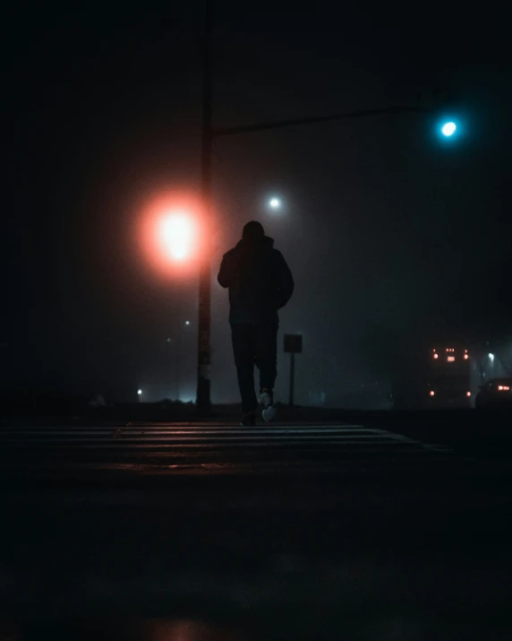 a man in a black coat walking across a street