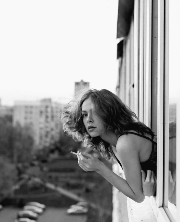 woman in black and white standing by window looking at view