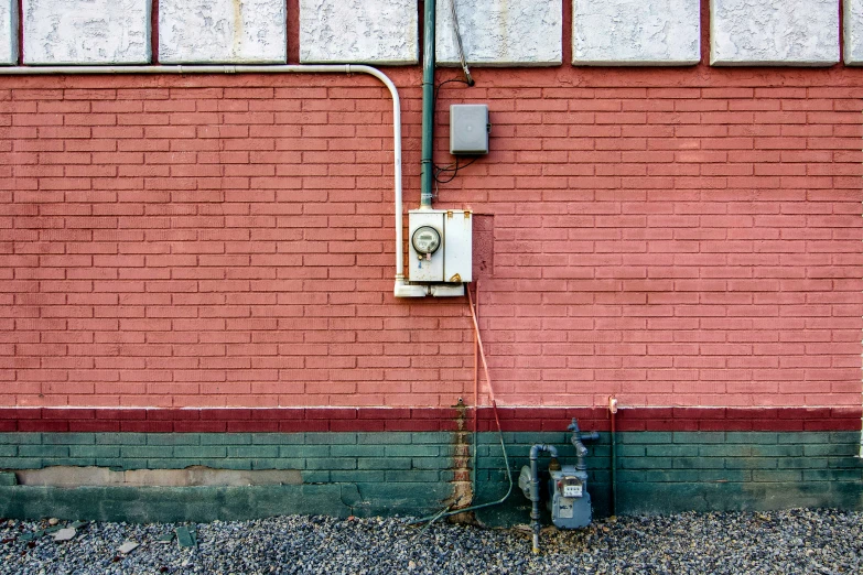 the red wall of a building is visible with a fire hydrant and power cable