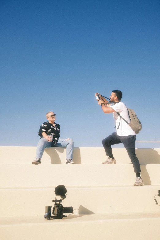 two men sitting on steps next to each other with a camera