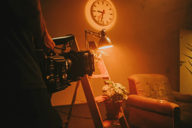 a person in dark living room with large clock and pographer