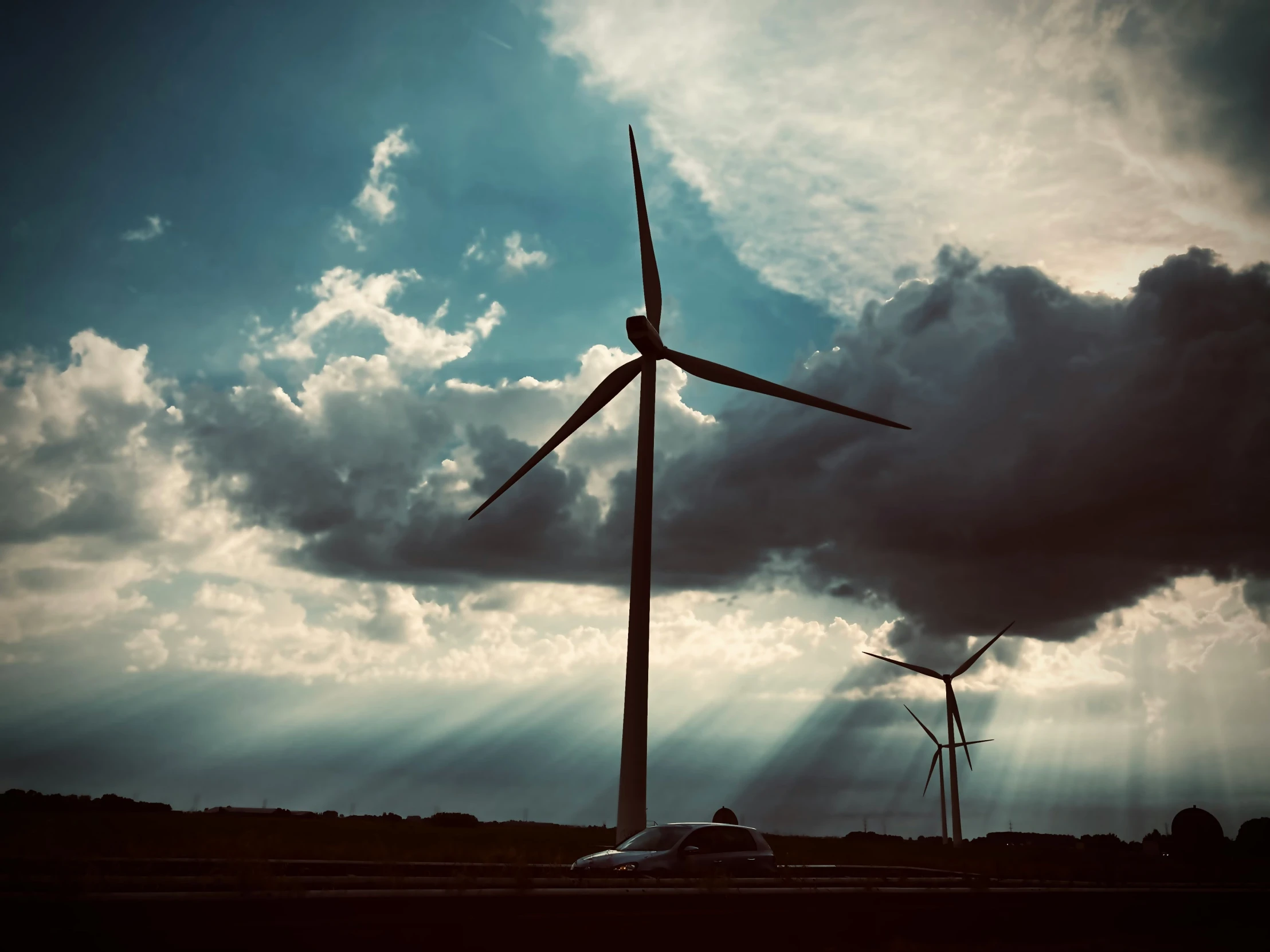 a car drives past a wind farm with several windmills in the background