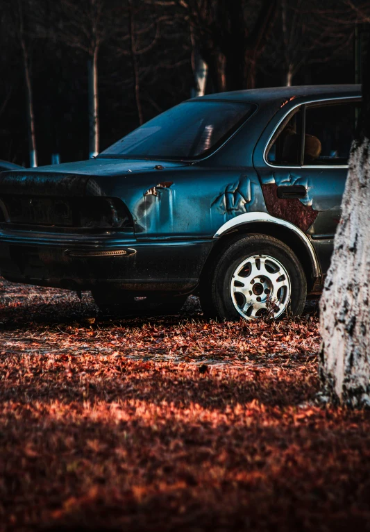 there is a blue car parked near a tree