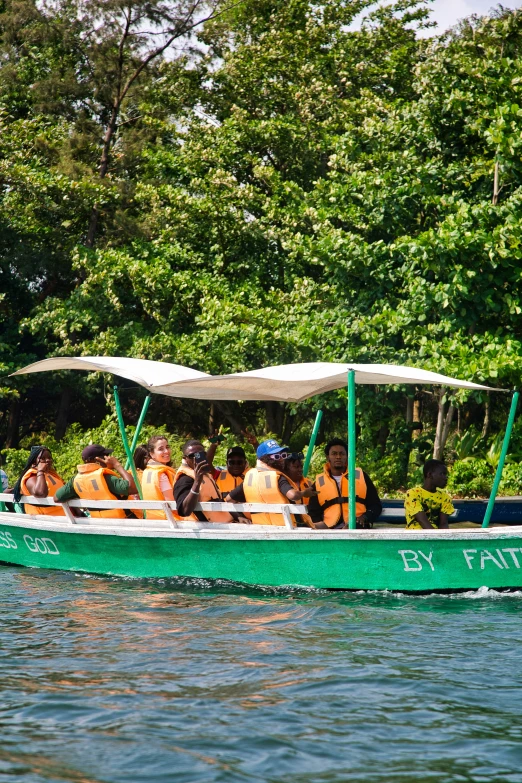 a long green boat filled with people on a lake