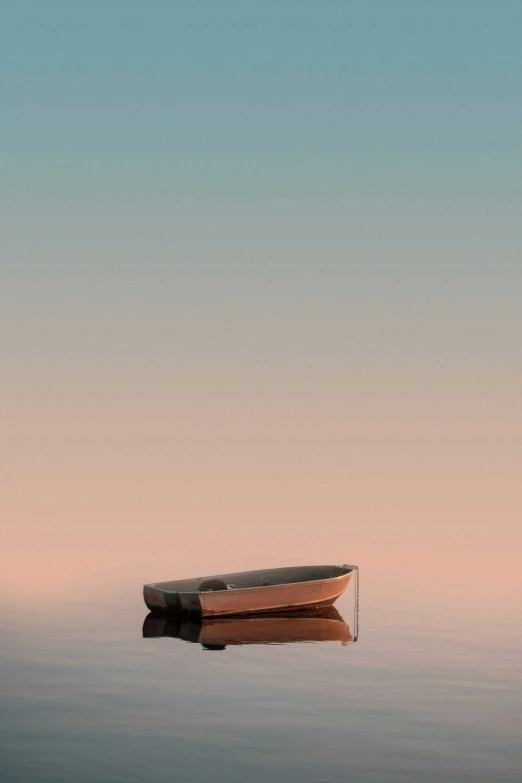 a boat sitting in a body of water under a pink and blue sky