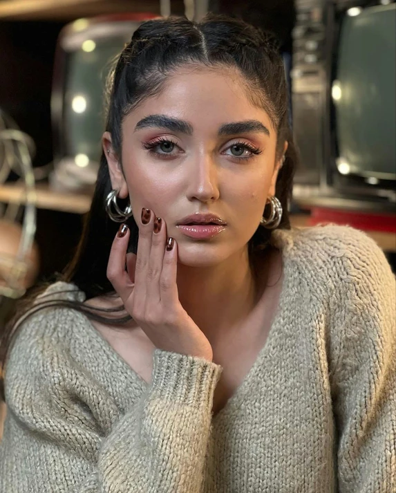 a woman with a ring and earrings on, posing for the camera