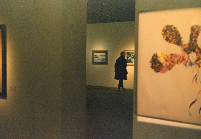 a man walking down a hallway with paintings