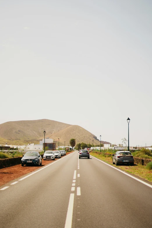 cars are parked along side the highway as a lamppost stands in the distance