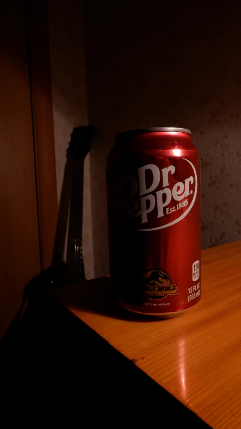a can of dr pepper sits on the wooden table
