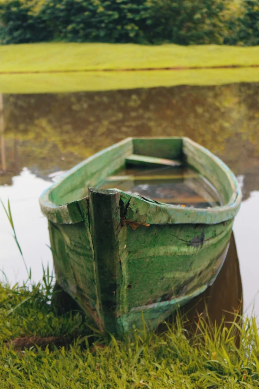 a wooden boat sitting on top of a lush green field