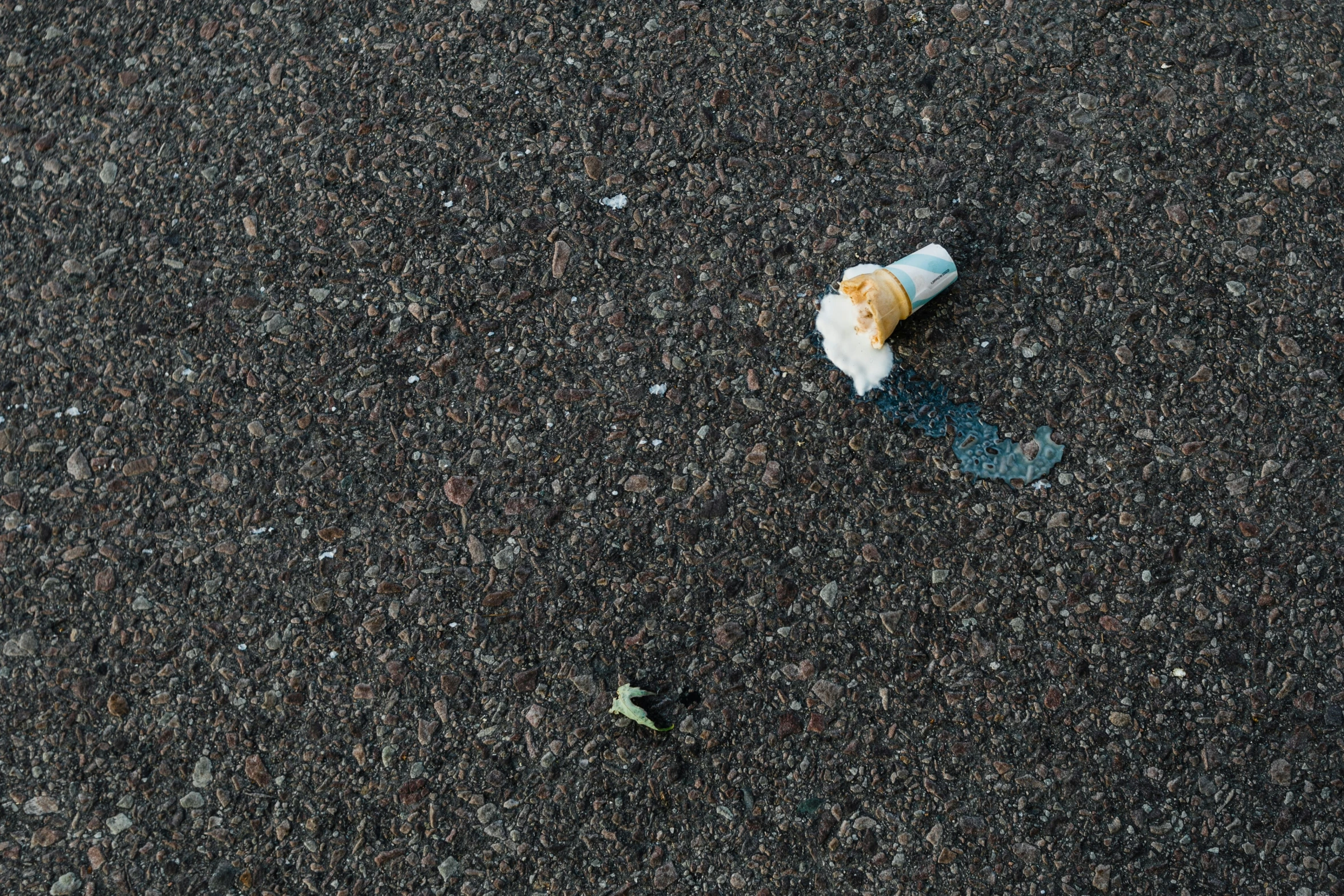 a discarded cigarette sitting on a black asphalt ground