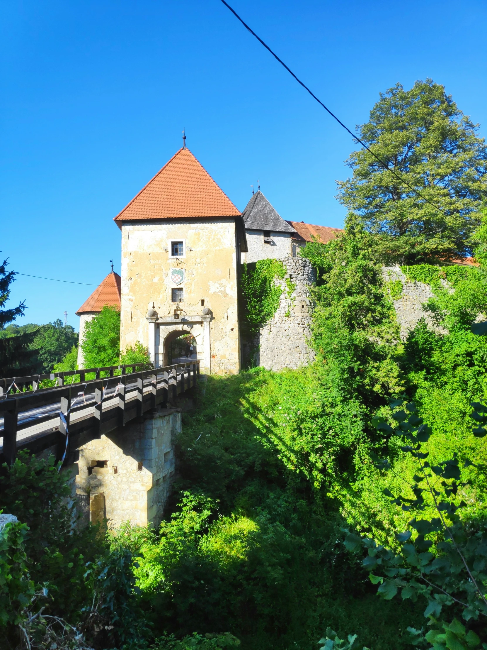 a stone castle surrounded by forest under a blue sky