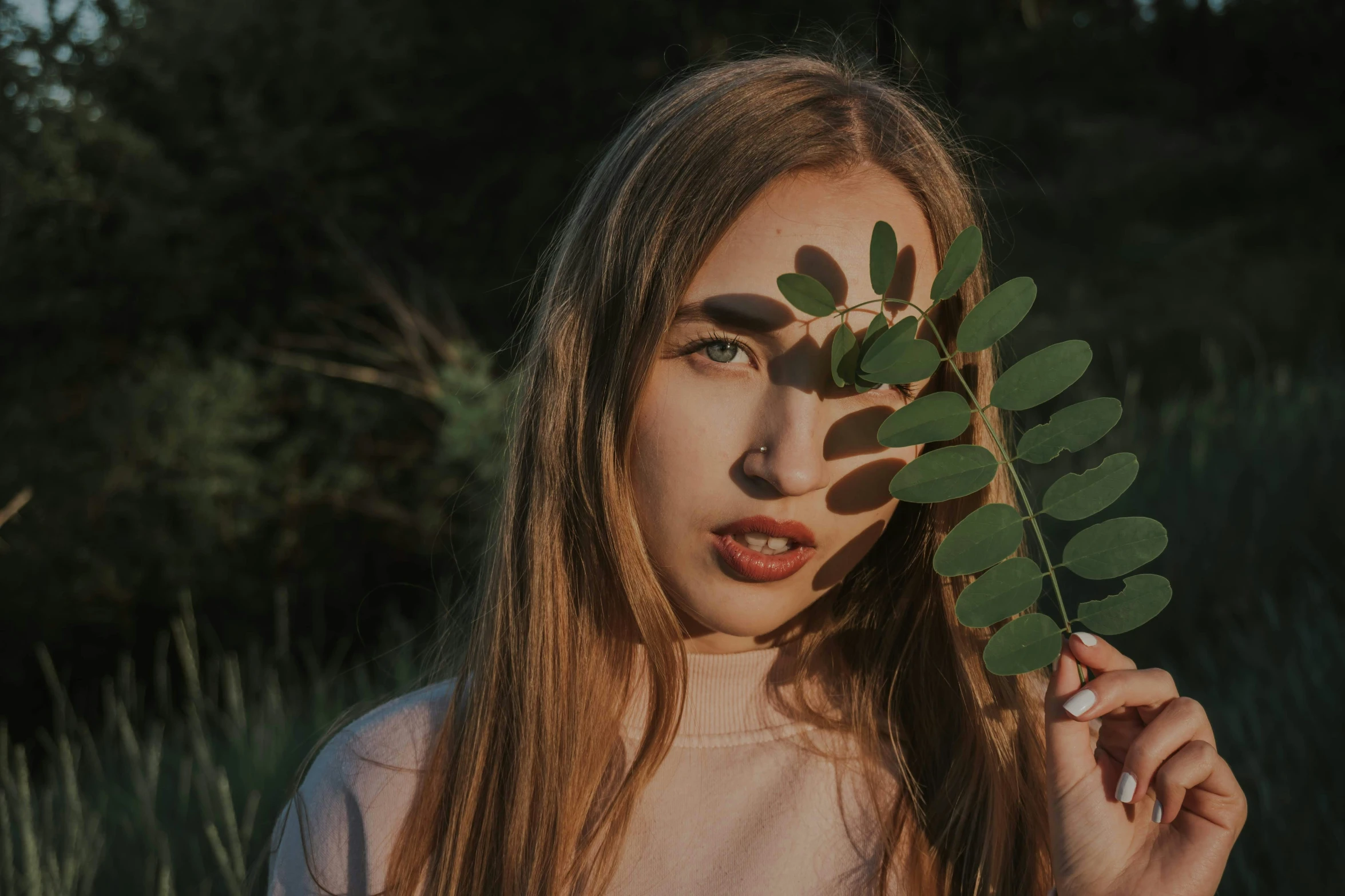 a girl holding out leaves to her face