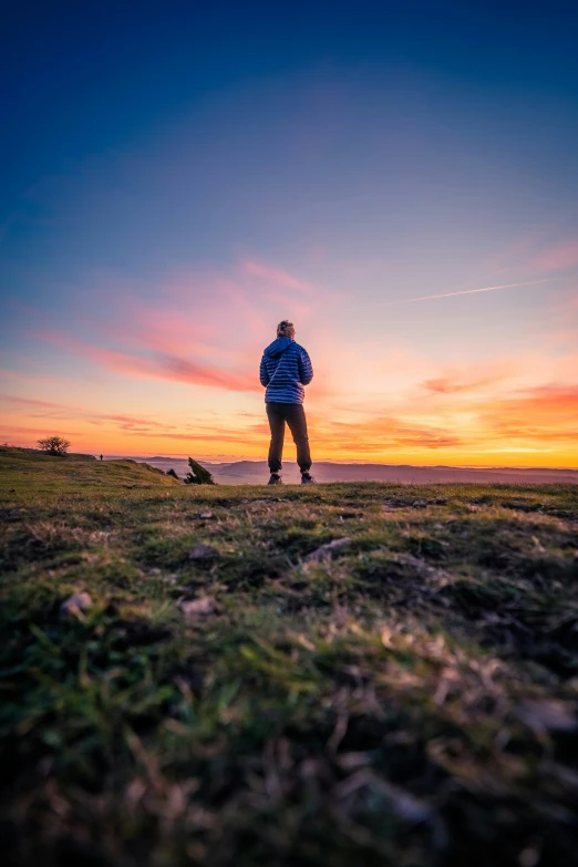 a person in a field with the sun setting behind them