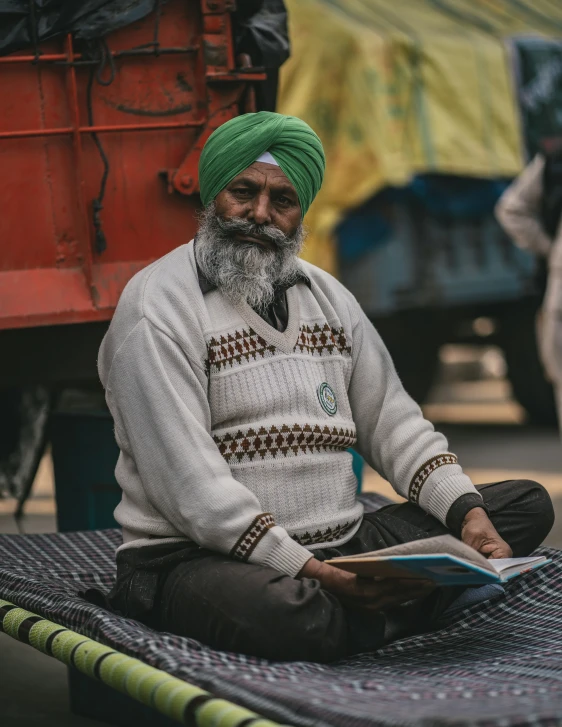 a man in white and green turban sitting on the ground