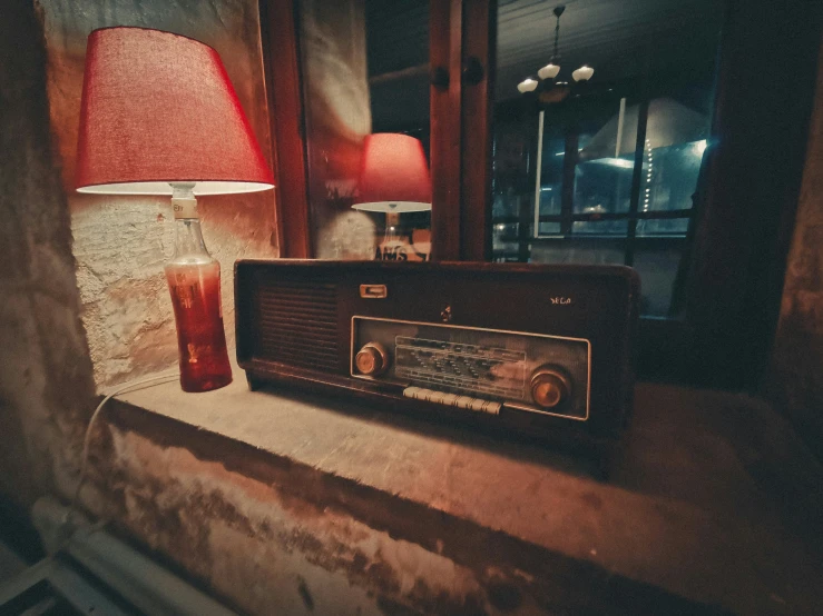 an old radio on the side of a stone wall with a lamp and table lamp nearby