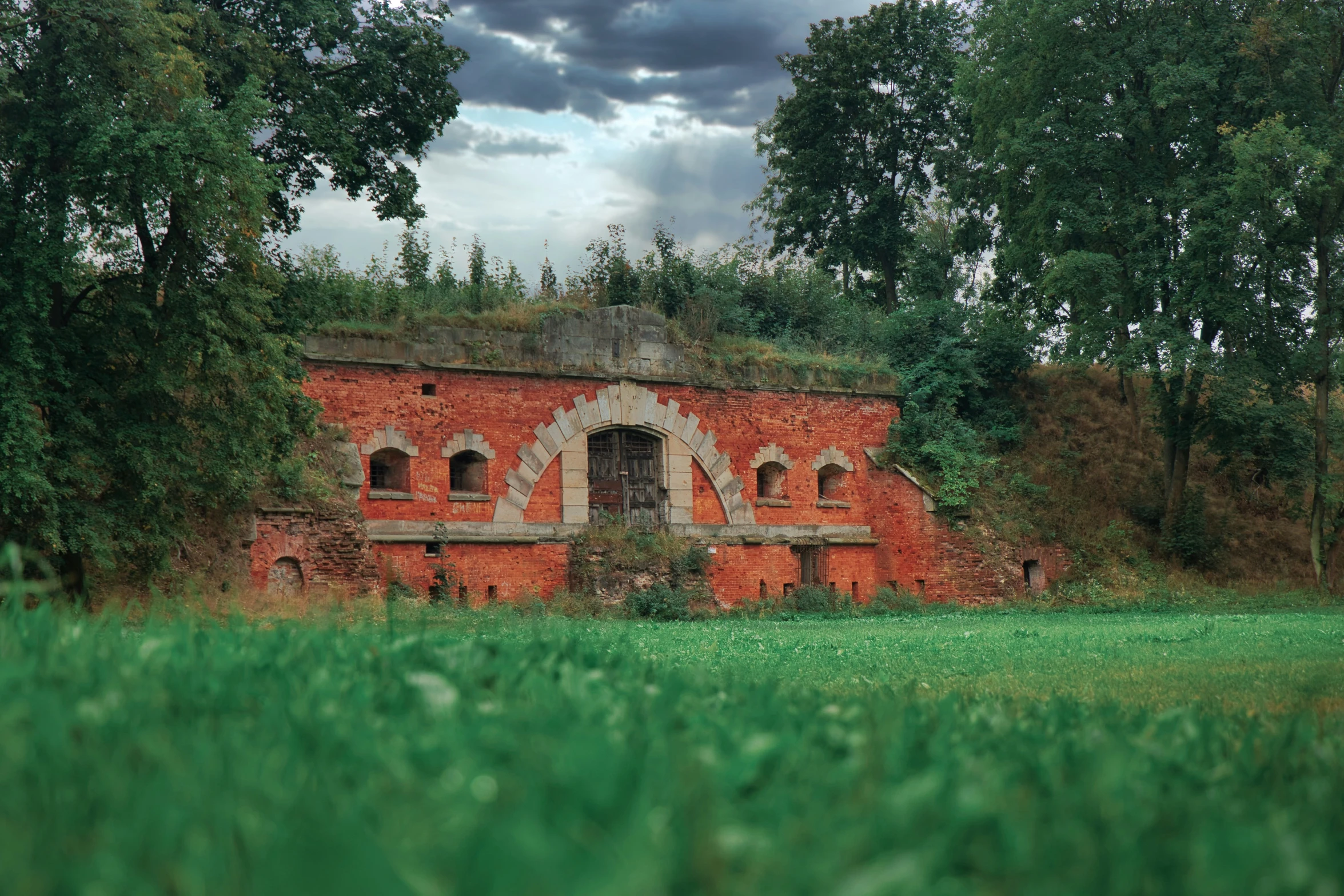 an old brick house in a lush green forest