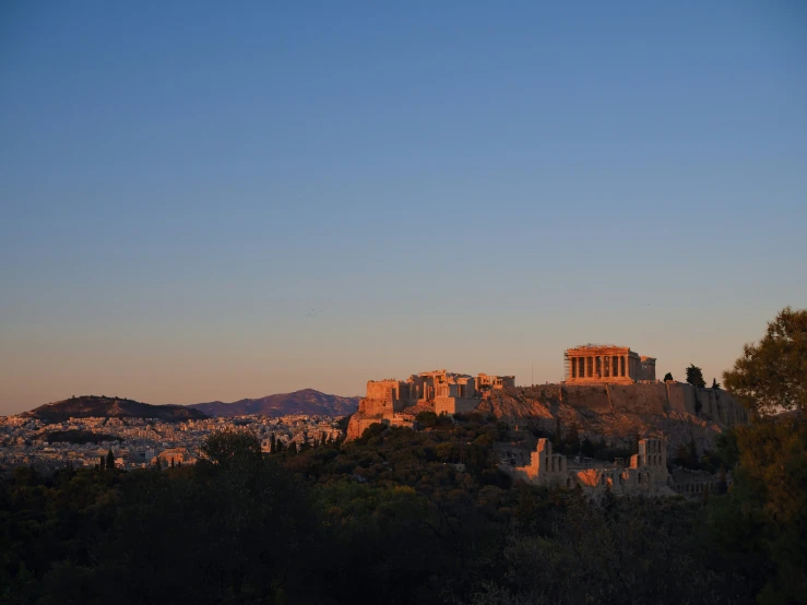 an ancient building atop the hill in front of some distant trees