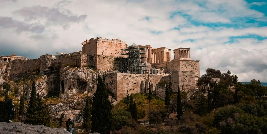 people standing outside of a large building on top of a hill