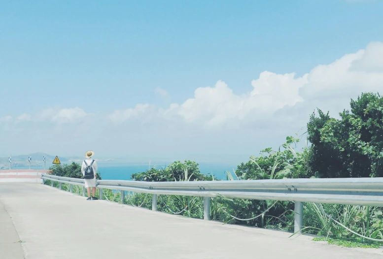 the woman is walking along the road near the ocean