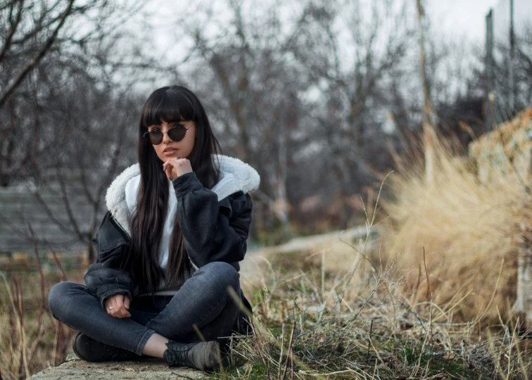 a woman is sitting in a field of grass