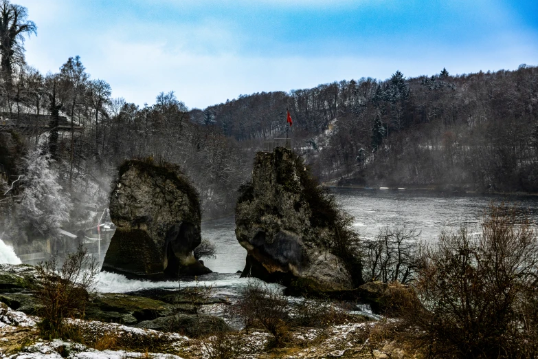 a lake with two rocks that have a mountain in the background