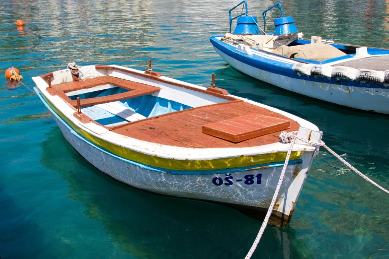 a small boat sits tied up with a smaller boat nearby