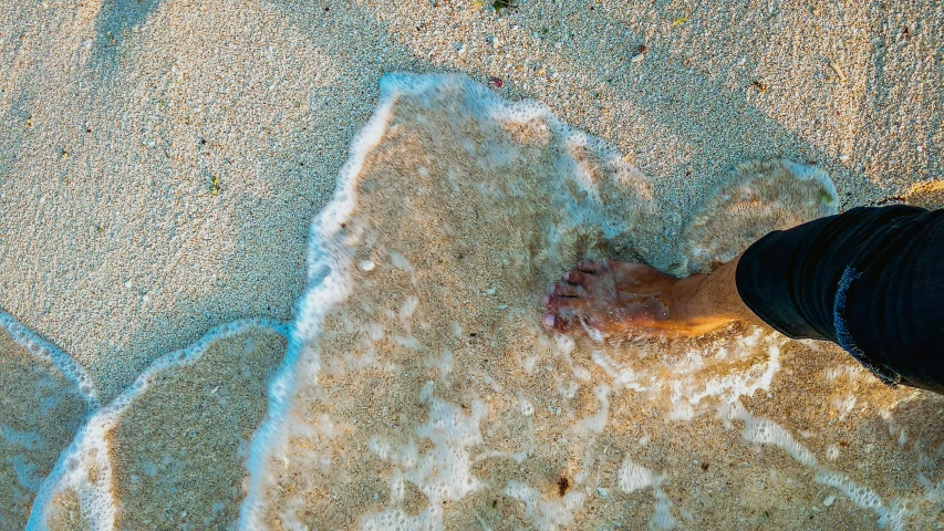 an aerial view of the bottom of someone's feet on the beach