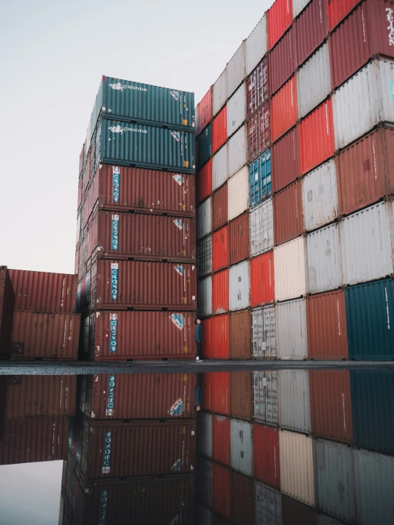 stacking containers reflecting in water with sky in background