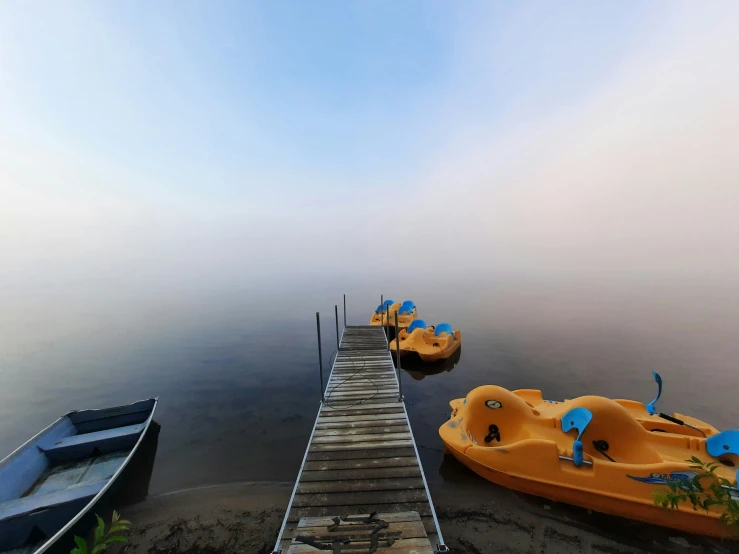 several boats are docked at the pier in the fog