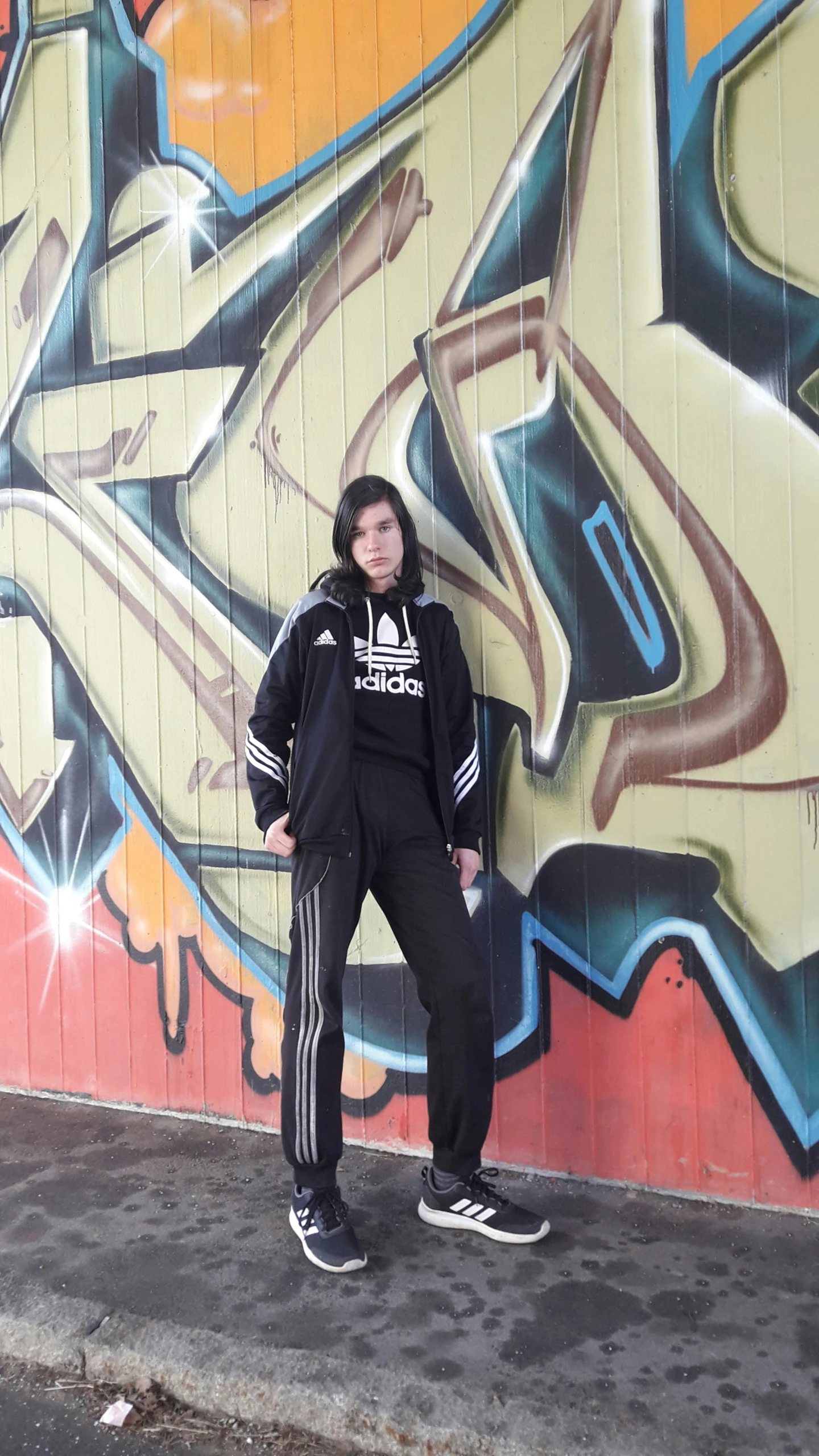 the young man stands in front of the graffiti wall