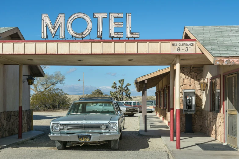 an old car parked under a motel sign