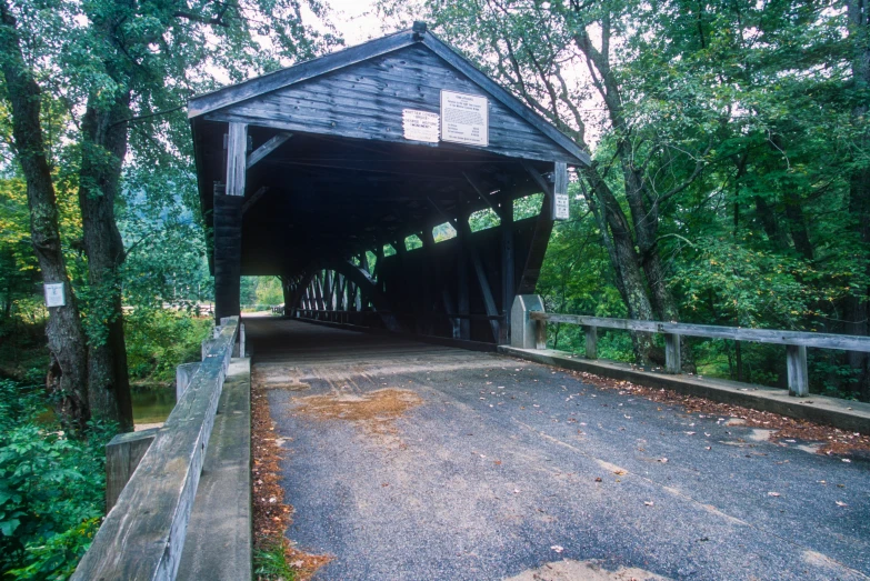 a covered bridge with road and trees in background