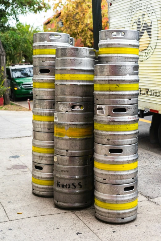 three metallic barrels stacked up on the sidewalk