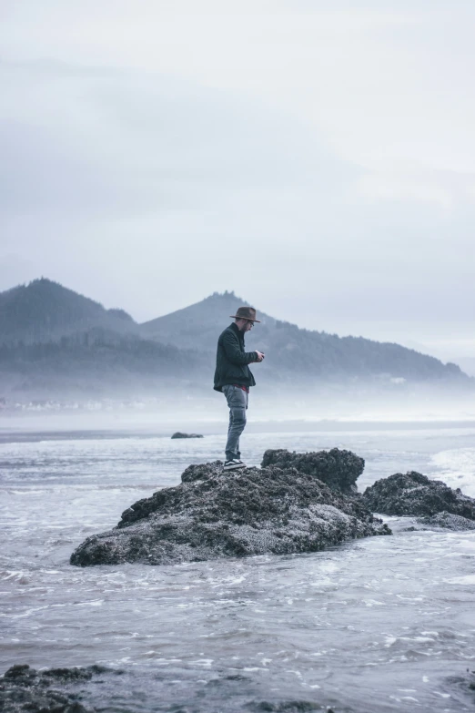 the person standing on a rock has a cell phone