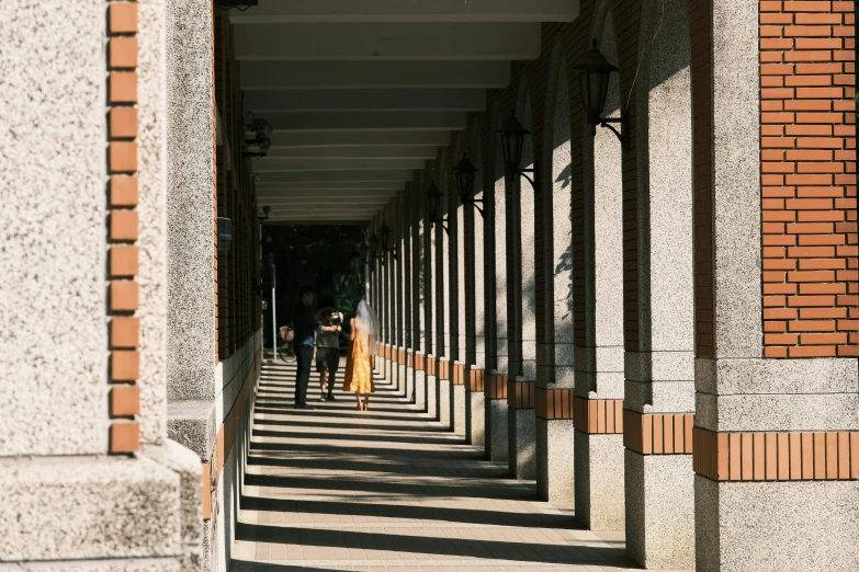 people walking underneath a row of long columns on the sidewalk