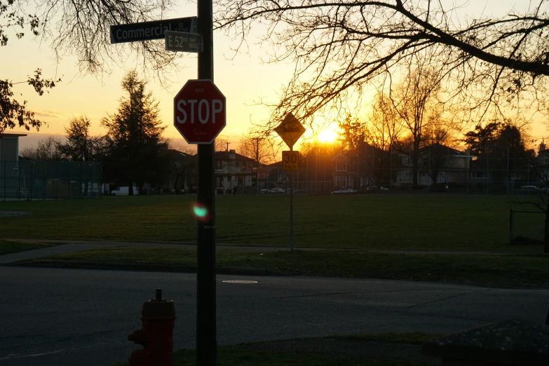 a street sign and stop sign on a metal pole in front of a fire hydrant