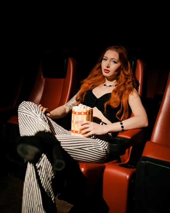 a girl with red hair and long stockings is sitting in a theater seat