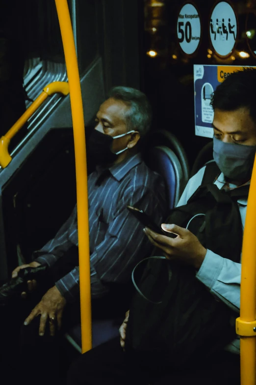 two men wear masks while riding on a bus