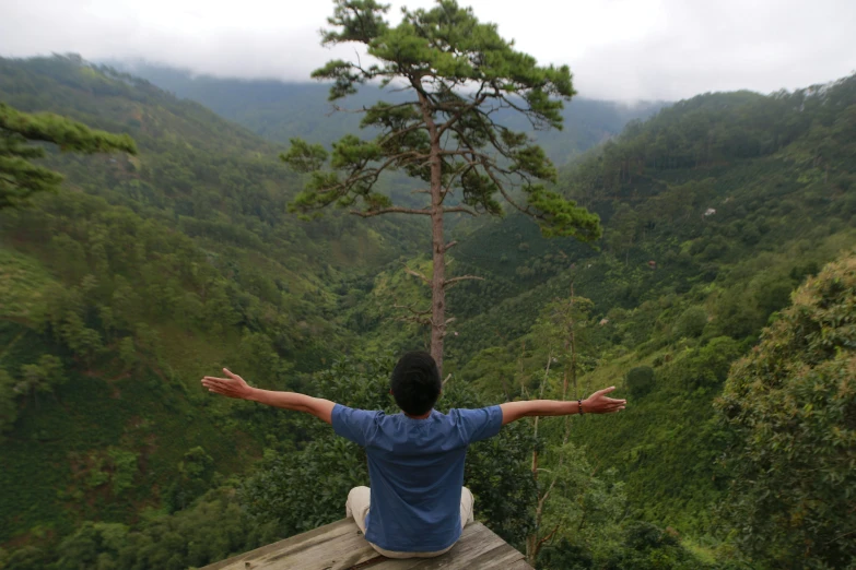 a man sitting on a ledge overlooking a valley